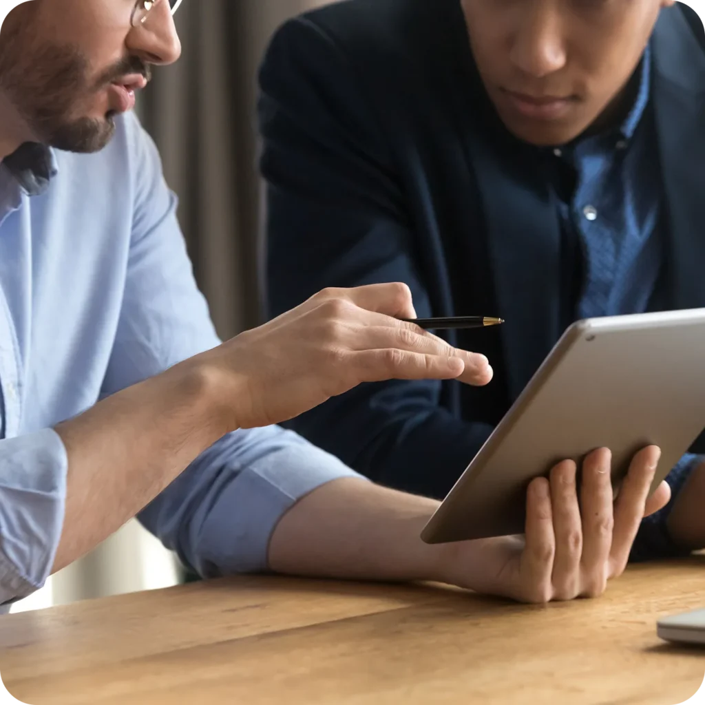 Two professionals reviewing information together on a tablet during a business meeting.